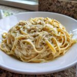 A close-up of creamy Cabbage Alfredo Pasta Recipe served in a white bowl, topped with dried herbs.