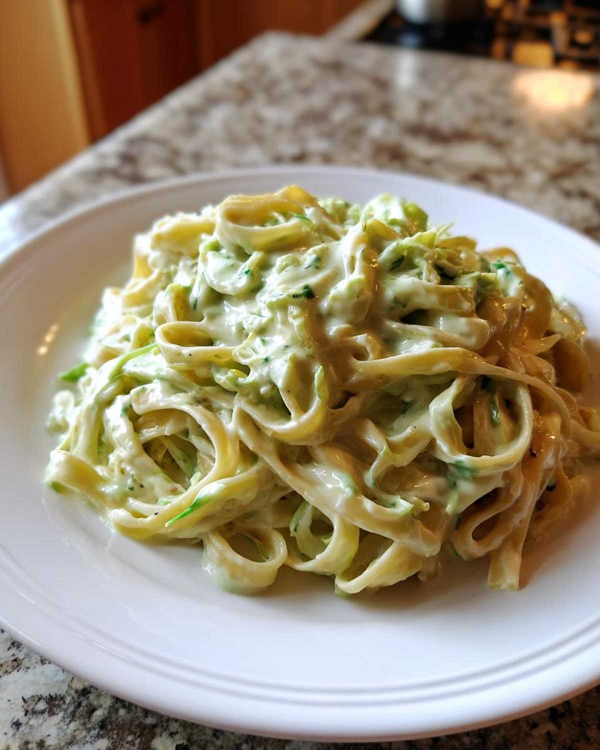 A close-up of fettuccine pasta coated in creamy Cabbage Alfredo Pasta Sauce, served on a white plate.
