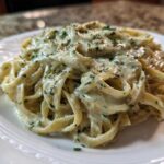 A close-up of fettuccine pasta generously coated in creamy Cabbage Alfredo Pasta Sauce and sprinkled with herbs.