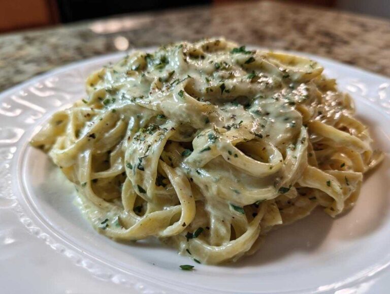 A close-up of fettuccine pasta generously coated in creamy Cabbage Alfredo Pasta Sauce and sprinkled with herbs.
