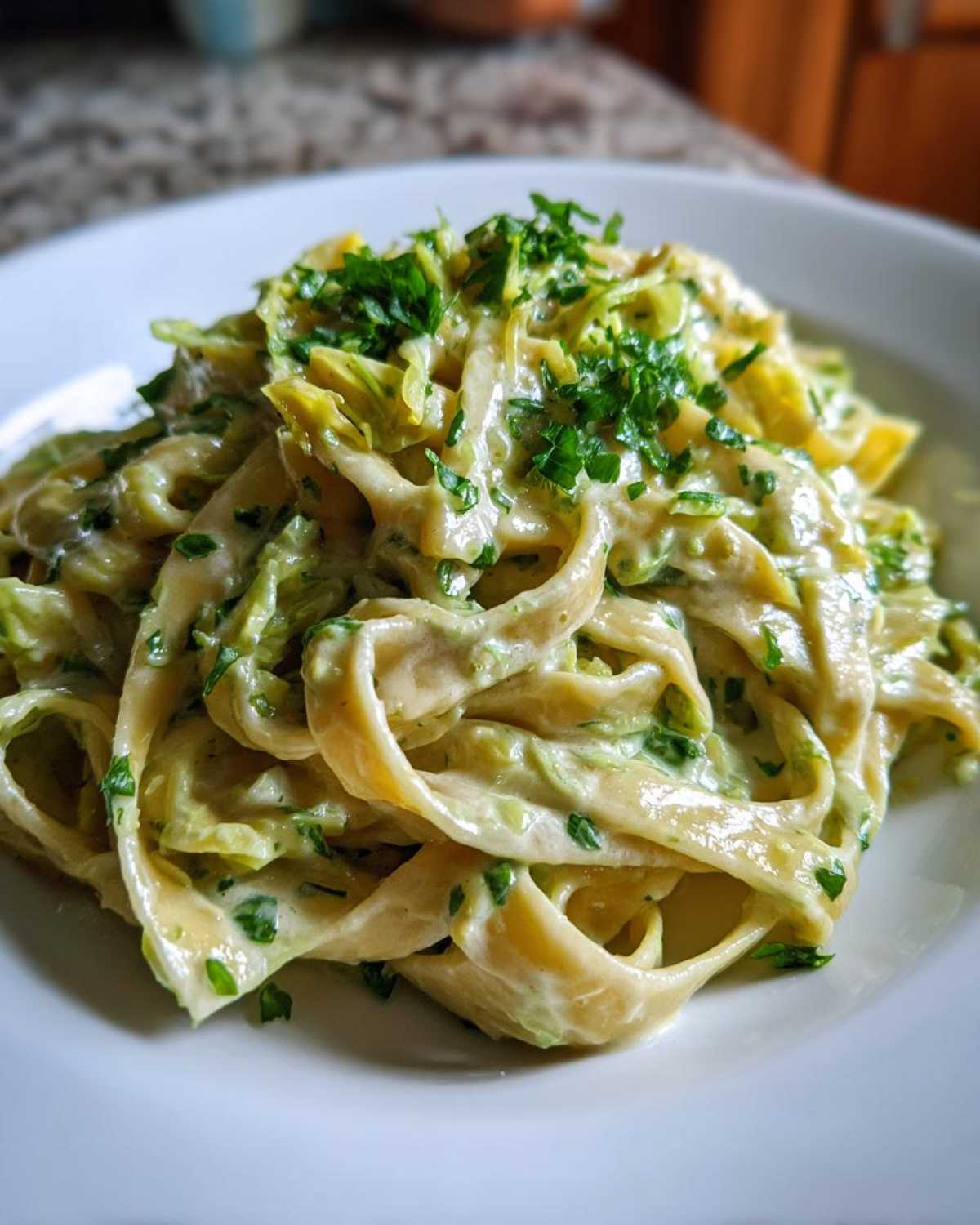 Close-up of fettuccine pasta coated in creamy Cabbage Alfredo Pasta Sauce and topped with fresh parsley.
