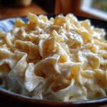 Close-up of creamy cottage cheese alfredo sauce coating ruffled egg noodles, topped with black pepper.