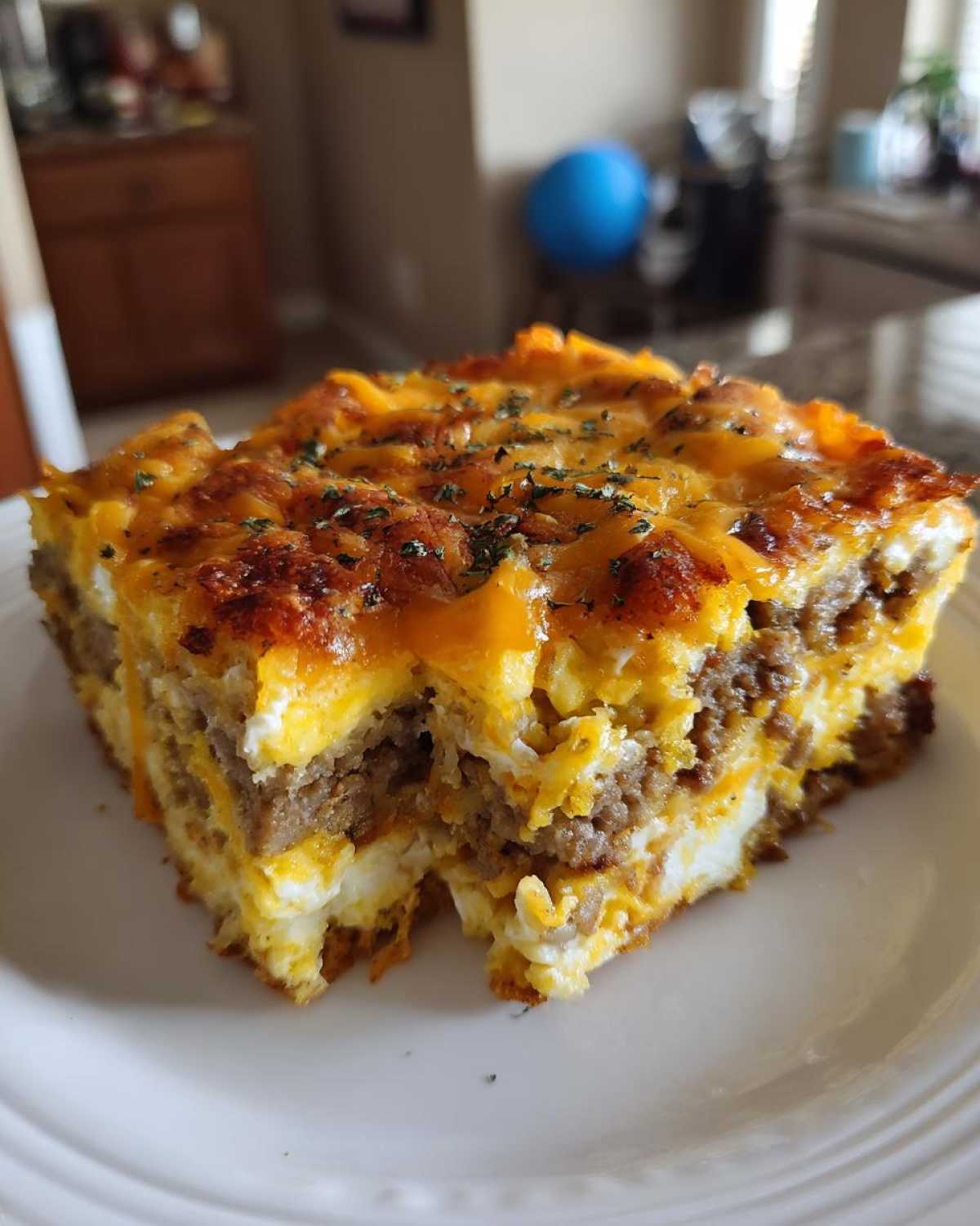 A square slice of layered Crescent Roll Breakfast Casserole featuring sausage, eggs, and melted cheddar cheese topping.