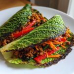 Two Crispy Cabbage Taco Wraps filled with seasoned ground meat, shredded carrots, and red pepper slices.