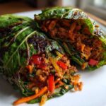 Two halves of Crispy Cabbage Taco Wraps filled with seasoned ground meat and vegetables, resting on a white plate.