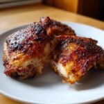 Close-up of three perfectly cooked, juicy chicken thighs with deeply browned, crispy skin.