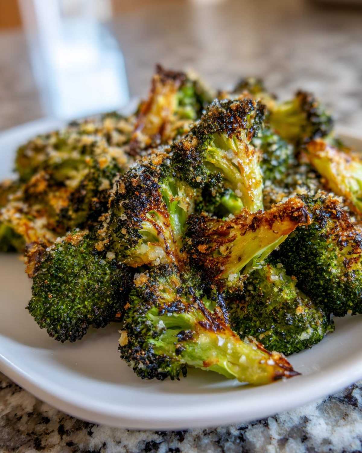 Close-up of perfectly roasted broccoli florets, slightly charred and topped with grated cheese.