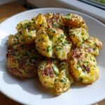 A pile of golden brown, crispy smashed potatoes topped with fresh chives and red onion, ready to be served as Crispy Smashed Potato Salad.