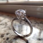 Close-up of a brilliant-cut diamond engagement ring with pavé detailing, perfect for those looking to Create Your Dream Ring.