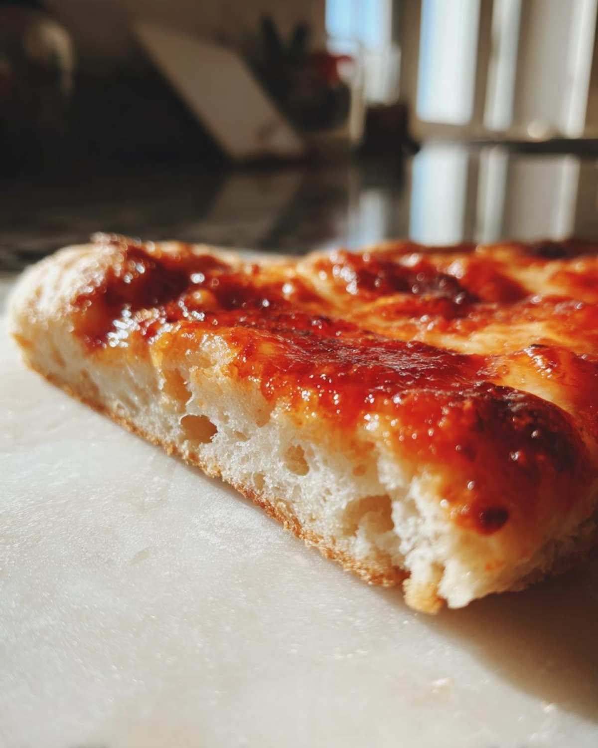 Close-up showing the airy, fluffy interior texture of a slice of keto pizza crust topped with bright red sauce.