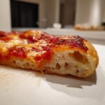 Close-up showing the airy, fluffy interior crumb structure of a slice of keto pizza crust topped with sauce and cheese.