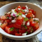 Close-up of a white bowl filled with Fresh Pico de Gallo Authentic salsa, showing diced tomatoes, onions, and cilantro.