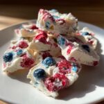 Close-up of broken pieces of Frozen Yogurt Bark with Spring Berries, featuring white yogurt mixed with red raspberries and blue blueberries.