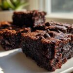 Close-up of fudgy Banana Bread Brownies squares topped with melted chocolate chips on a white plate.