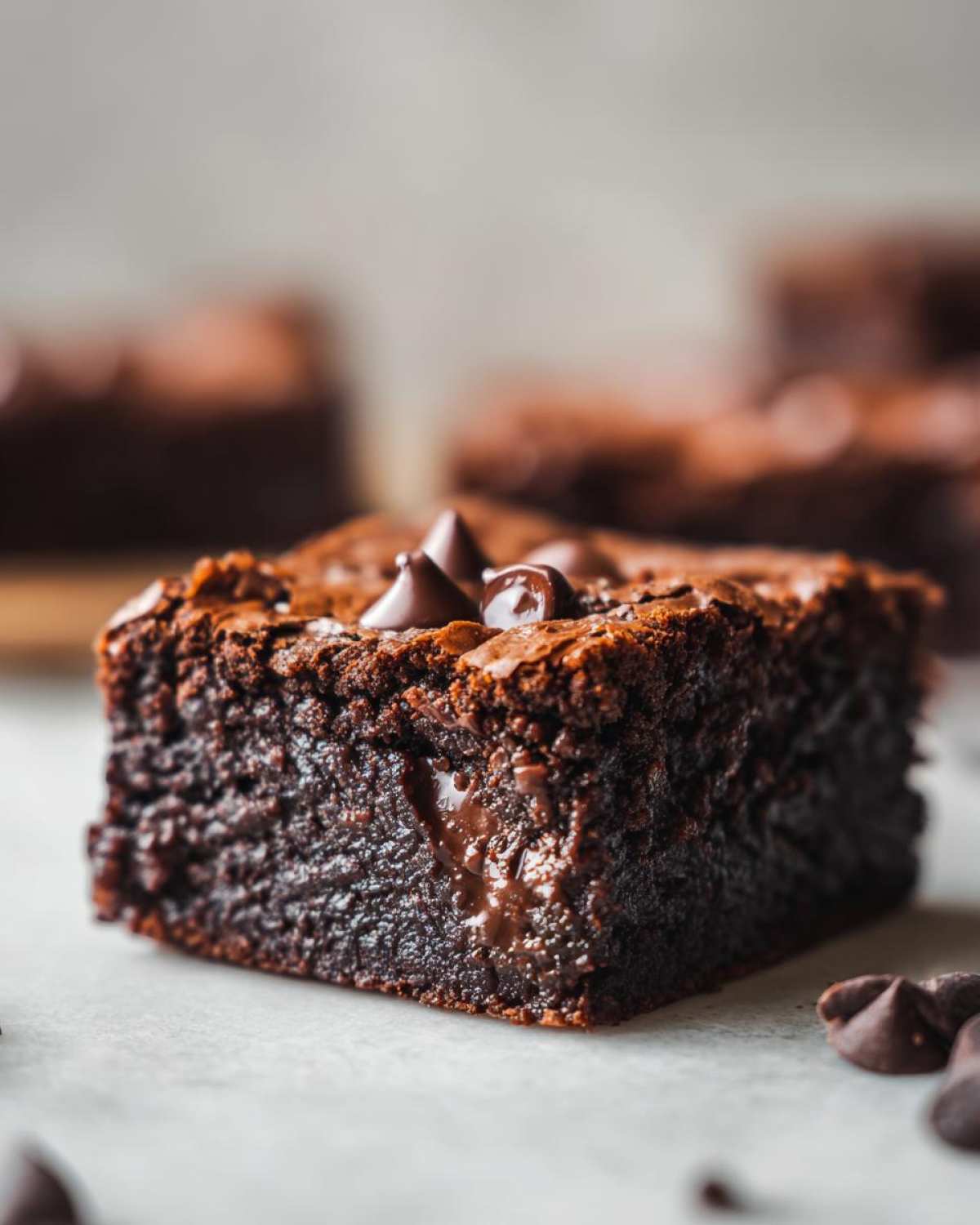 A close-up, decadent square of fudgy chocolate cobbler topped with melted chocolate chips.
