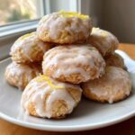 A stack of delicious italian ricotta cookies topped with white lemon glaze and bright yellow lemon zest.