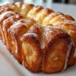 Close-up of a golden brown, freshly baked Pull Apart Easter Bunny Bread drizzled with white icing.