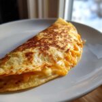 Close-up of a golden-brown, folded cheesy pocket tacos overflowing with melted cheddar cheese.
