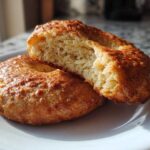 Two golden brown Cottage Cheese Bagels on a white plate, one is split open showing the soft interior texture.