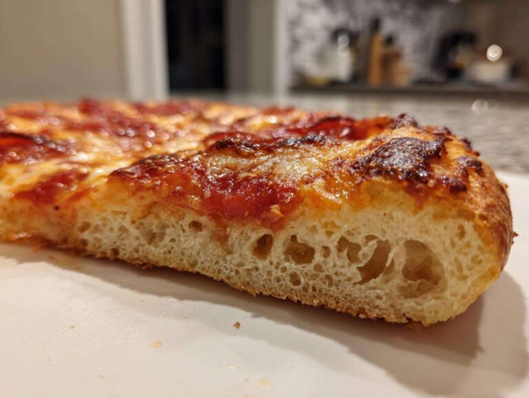 Close-up of a thick slice showing the airy crumb structure of the keto pizza crust topped with melted cheese and pepperoni.
