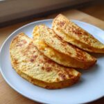 Four golden-brown Keto Taco Shells with Melted Cheese folded and arranged on a white plate.