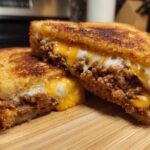 Close-up of a grilled sandwich cut in half, showing melted cheese and savory leftover meatloaf filling for the Leftover Meatloaf Sandwich Recipe.