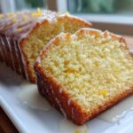 Close-up of a slice of moist Lemon Olive Oil Pound Cake drizzled with white glaze and lemon zest.