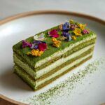 A rectangular slice of layered Matcha Tiramisu topped with vibrant edible flowers and dusted with matcha powder.