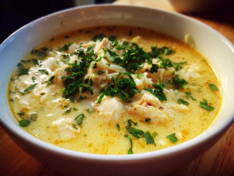Close-up of a bowl of creamy Mediterranean Lemon Chicken Soup, topped with shredded chicken and fresh parsley.