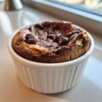A single, puffed Mini Chocolate Dutch Baby Pancake baked in a white ramekin.