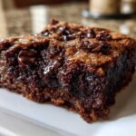 Close-up of a rich, fudgy slice of chocolate cobbler showing melted chocolate chips on a white plate.