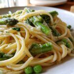 Close-up of creamy One Pot Spring Pasta Primavera featuring bright green asparagus spears and peas tossed with linguine.