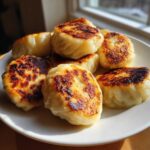 A plate piled high with golden brown, pan fried Cabbage Dumplings, showing crispy, seared edges.