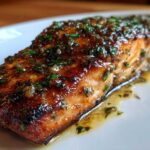 A perfectly cooked fillet of Pan Seared Garlic Butter Salmon, glistening with butter sauce and herbs.