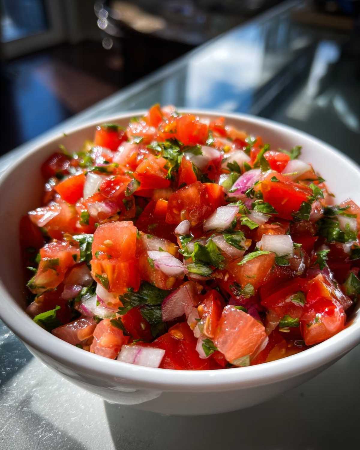 Close-up of fresh, chunky Pico De Gallo Recipe Zesty ingredients including diced tomatoes, red onion, and cilantro in a white bowl.