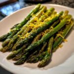 A close-up of perfectly Roasted Asparagus with Lemon and Parmesan served on a white plate.