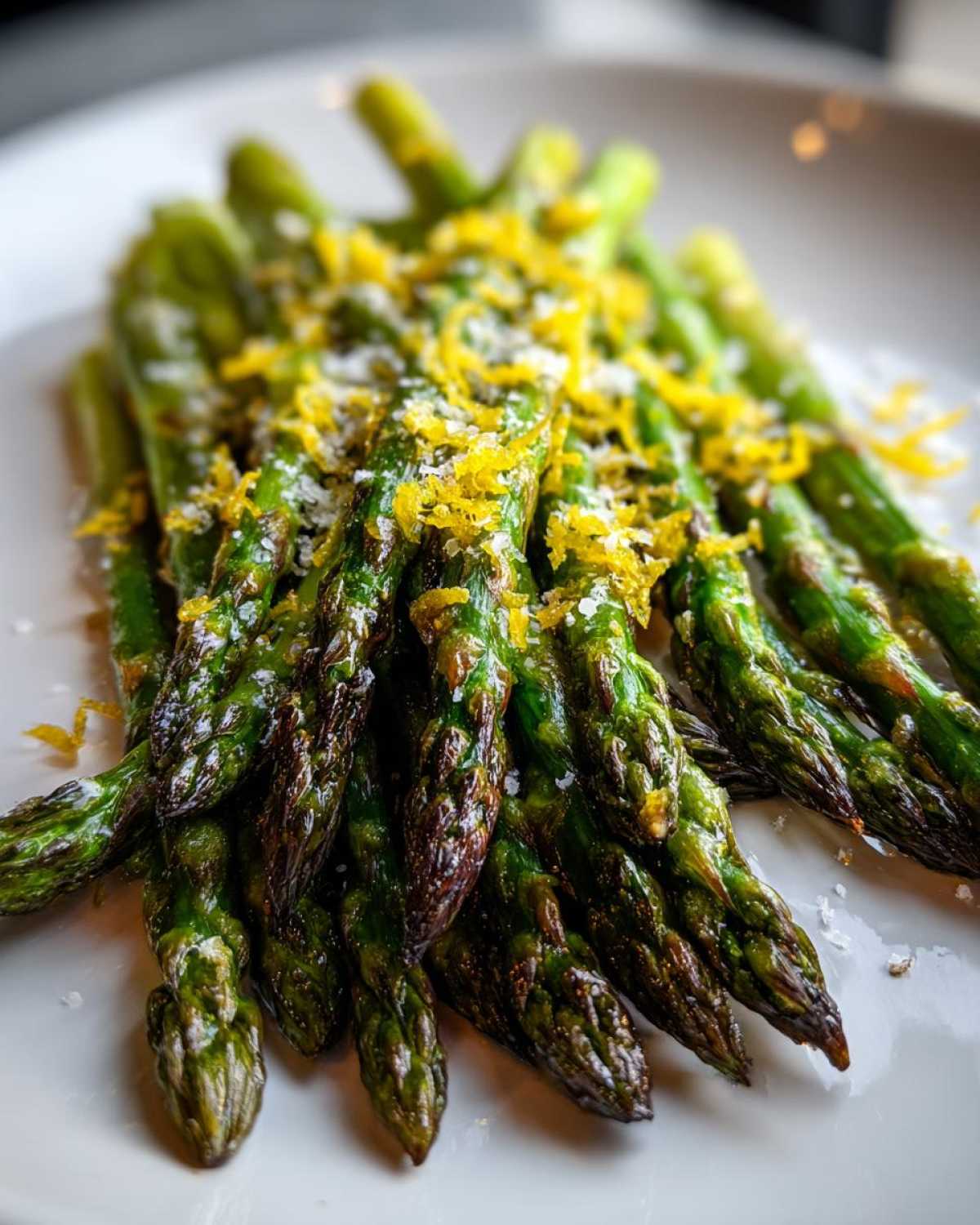 Close-up of perfectly Roasted Asparagus with Lemon and Parmesan, topped with bright yellow zest.