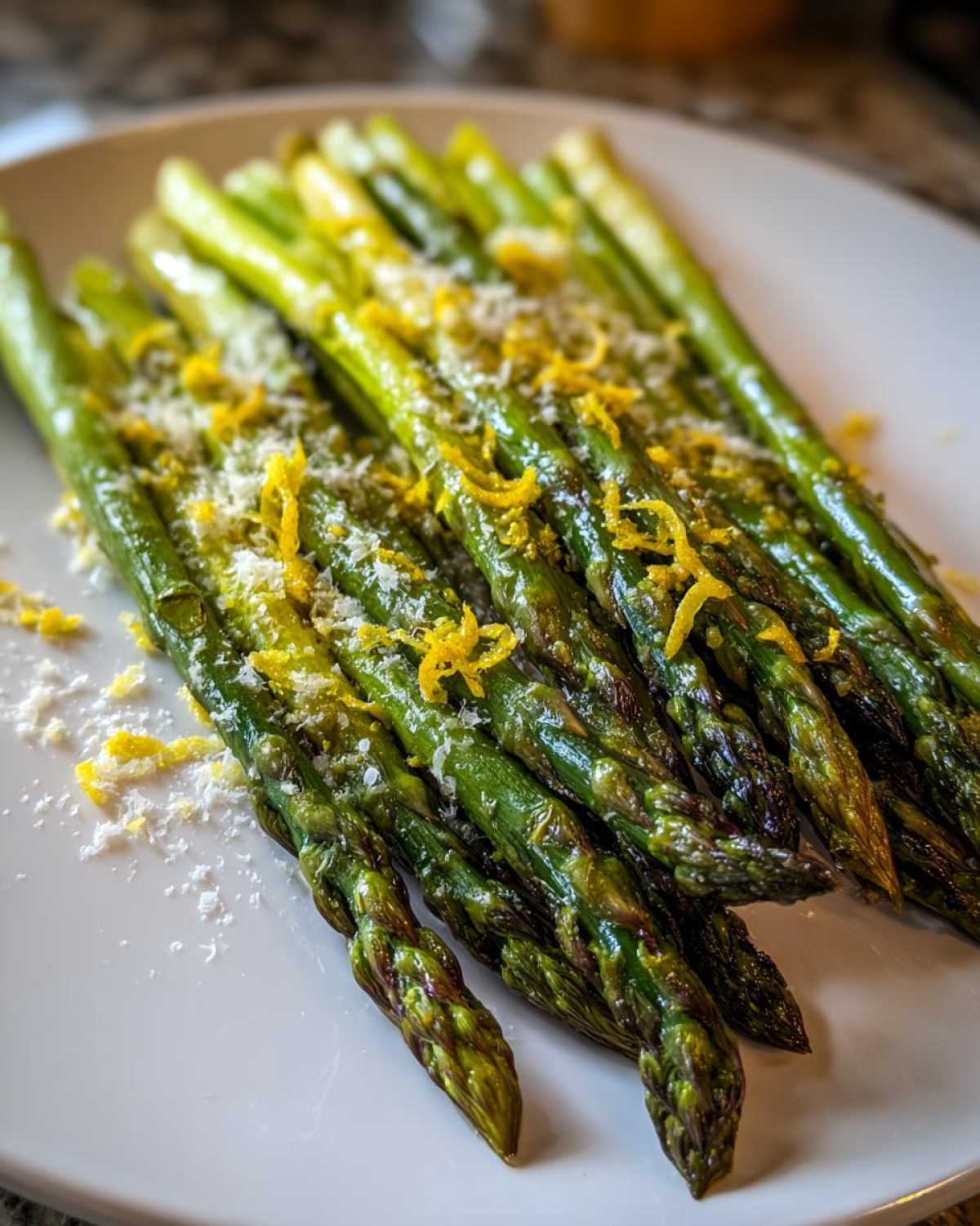 Close-up of bright green Roasted Asparagus with Lemon and Parmesan served on a white plate.