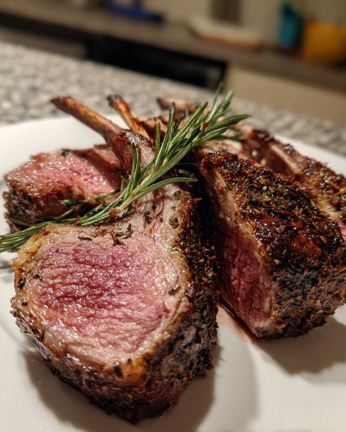 Close-up of perfectly cooked Roasted Lamb Chops with Garlic Rosemary, showing medium-rare pink center and herb crust.