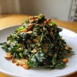 A mound of dark green kale coated in creamy dressing, topped with roasted peanuts and green onions, served as a Roasted Peanut Kale Crunch Salad.