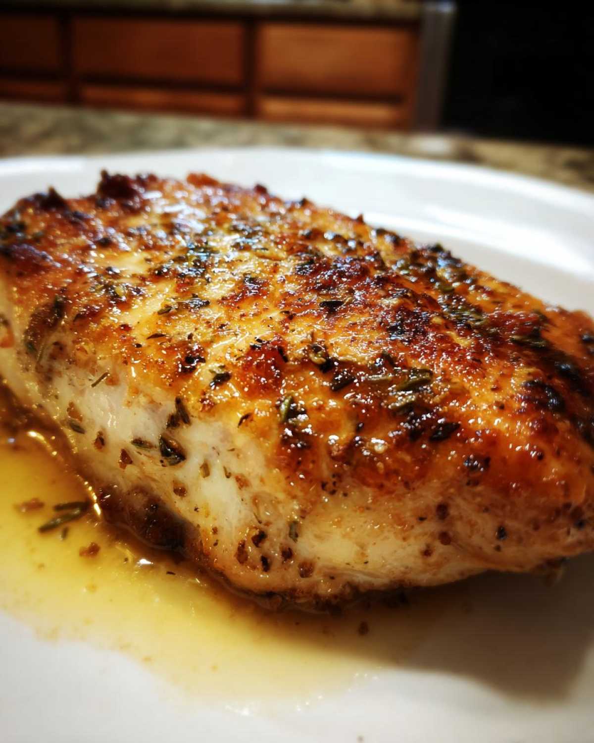 Close-up of a juicy, pan-seared cajun chicken breast with a golden-brown crust and herbs.