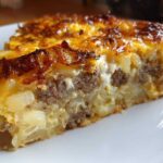 Close-up of a hearty slice of breakfast casserole with cream of mushroom, showing layers of sausage, potatoes, and a golden-brown cheesy top.
