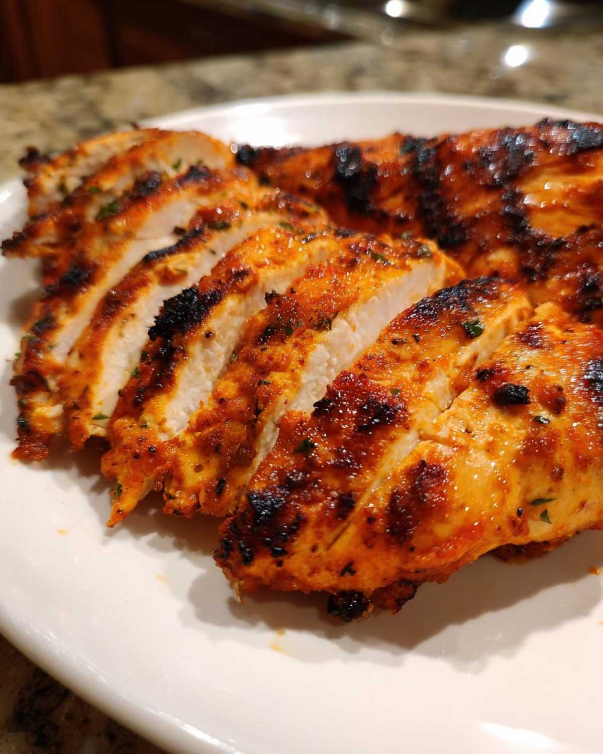 Close-up of sliced, grilled Fiesta Lime Chicken showing juicy white meat and vibrant orange-red seasoning.