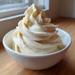 A perfect swirl of creamy, pale yellow banana ice cream served in a small white bowl.