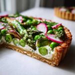 Close-up cross-section of a Spring Vegetable Tart with Puff Pastry showing asparagus, peas, and radish on a creamy filling.