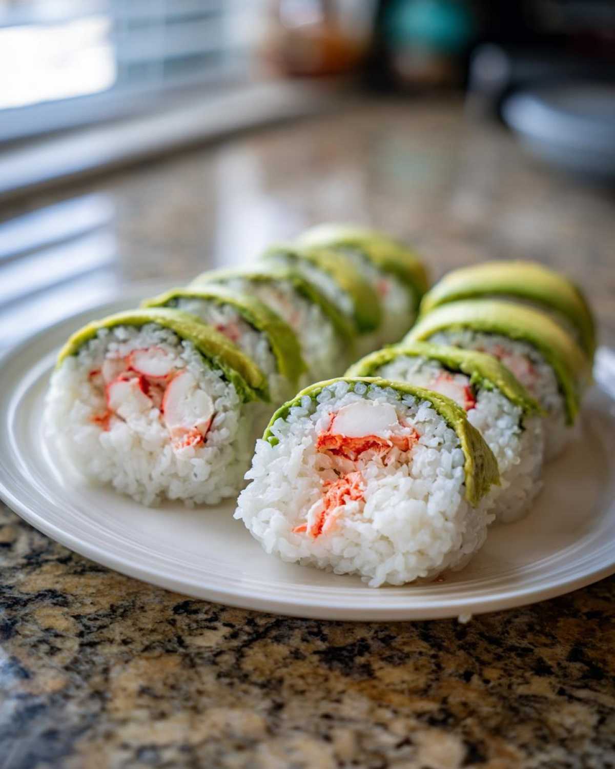 Close-up of several slices of California Sushi Roll topped with avocado, showing crab filling and white rice.