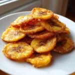 A close-up stack of crispy Cinnamon Sugar Air Fryer Banana Chips dusted heavily with cinnamon and sugar.