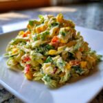 A close-up of a serving of creamy Jalapeno Corn Coleslaw piled high on a square white plate.