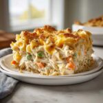 A generous slice of creamy Turkey Casserole featuring shredded meat, peas, carrots, and a golden, cheesy, crunchy topping.