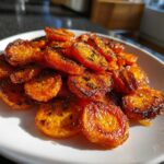 Close-up of shiny, caramelized Crispy Smashed Carrot Bites Oven Roasted Snack or Side Dish sprinkled with herbs.